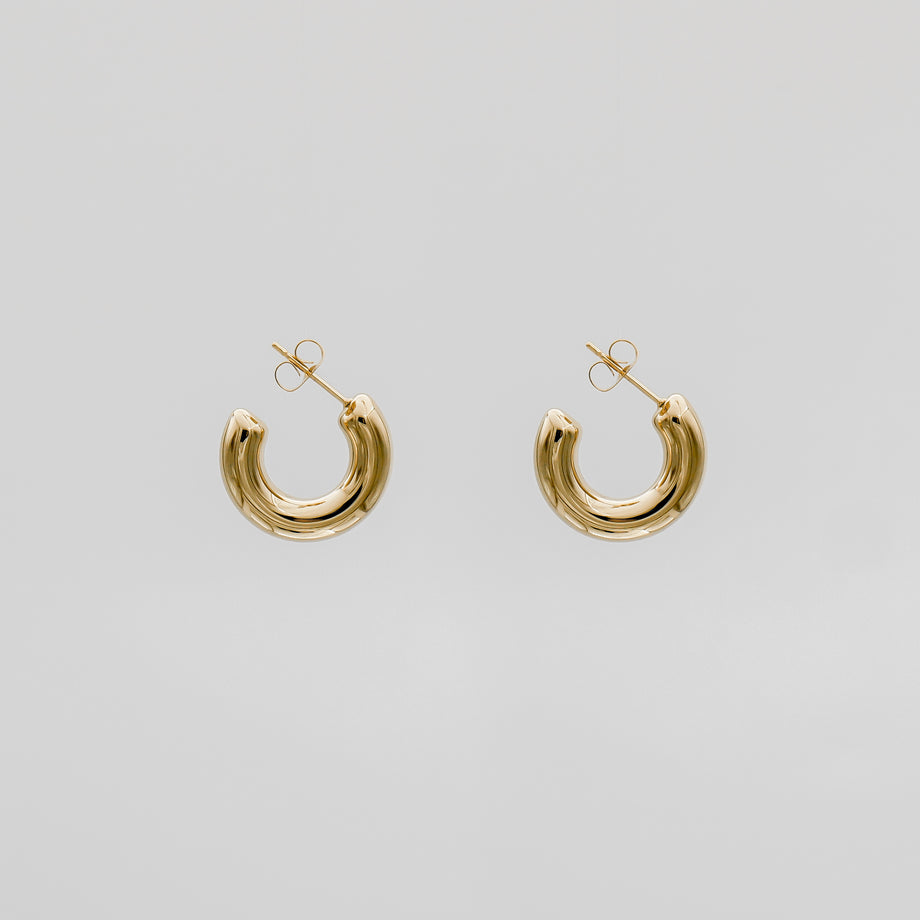 Gold hoop earrings on a plain background.