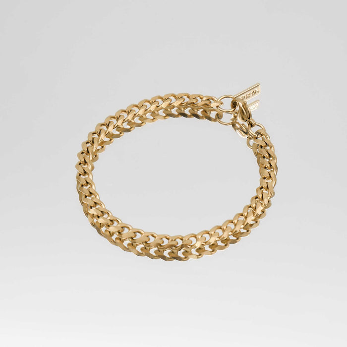 Gold chain bracelet on grey background.