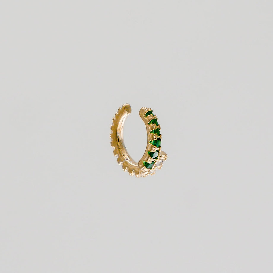 Gold hoop earring with green gemstones.