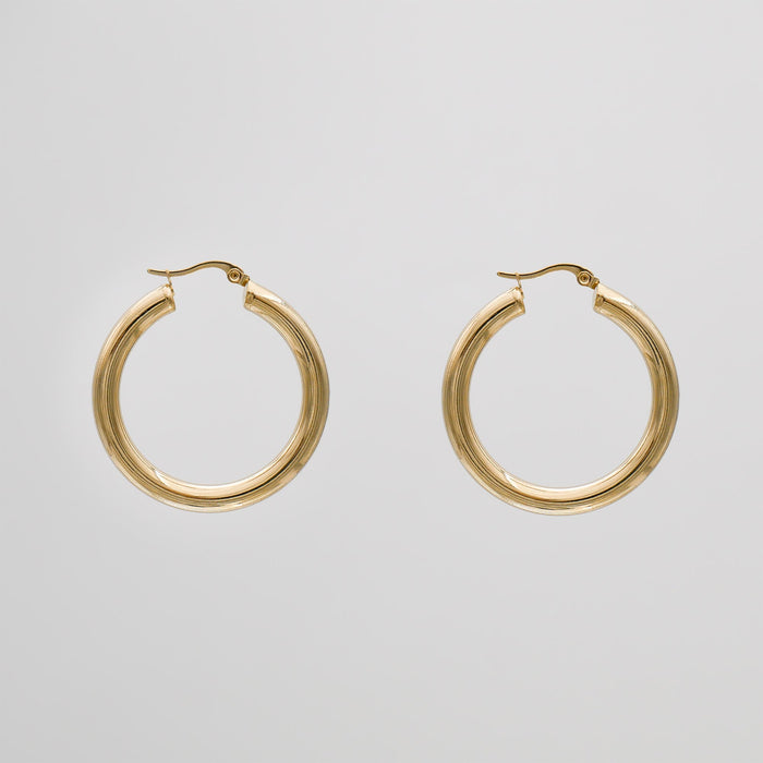 Gold hoop earrings on a grey background.