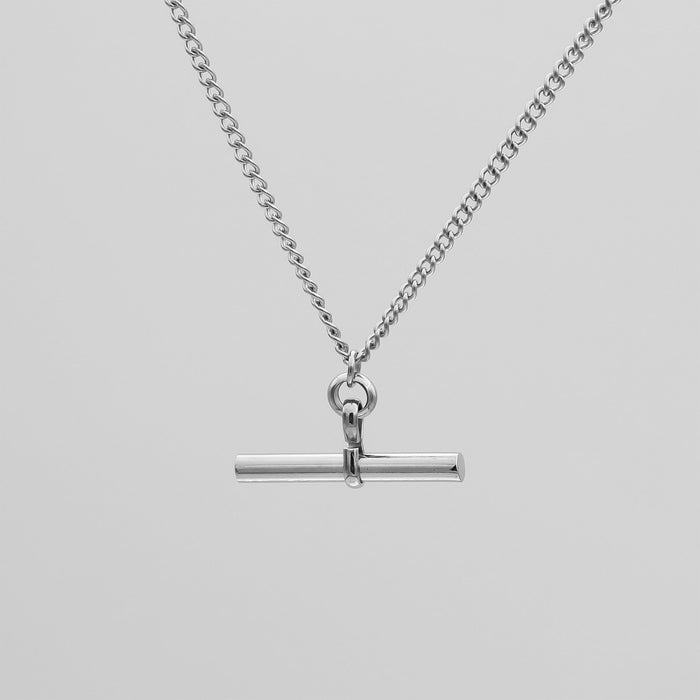 Silver necklace with bar pendant on chain.