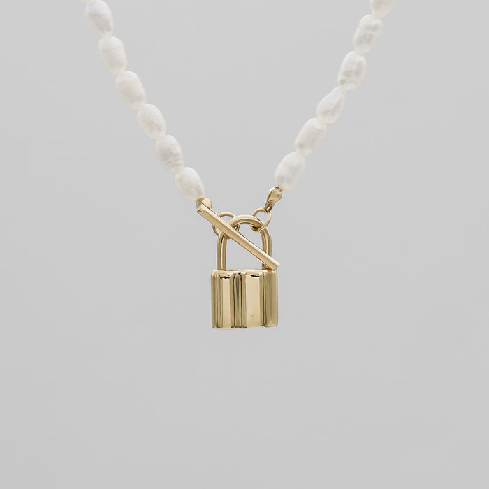 Gold lock pendant on pearl necklace.