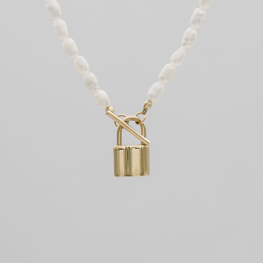 Gold lock pendant on pearl necklace.