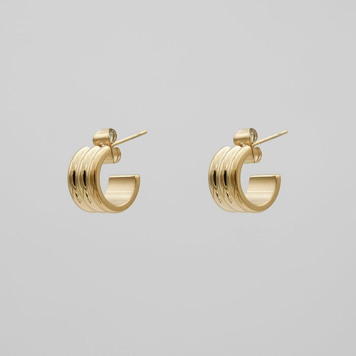 Gold hoop earrings on a grey background.