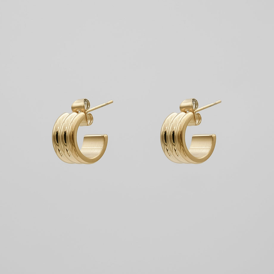 Gold hoop earrings on a grey background.