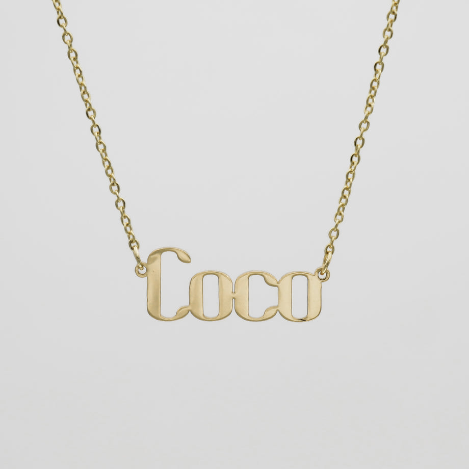 Gold "Coco" necklace on white background.