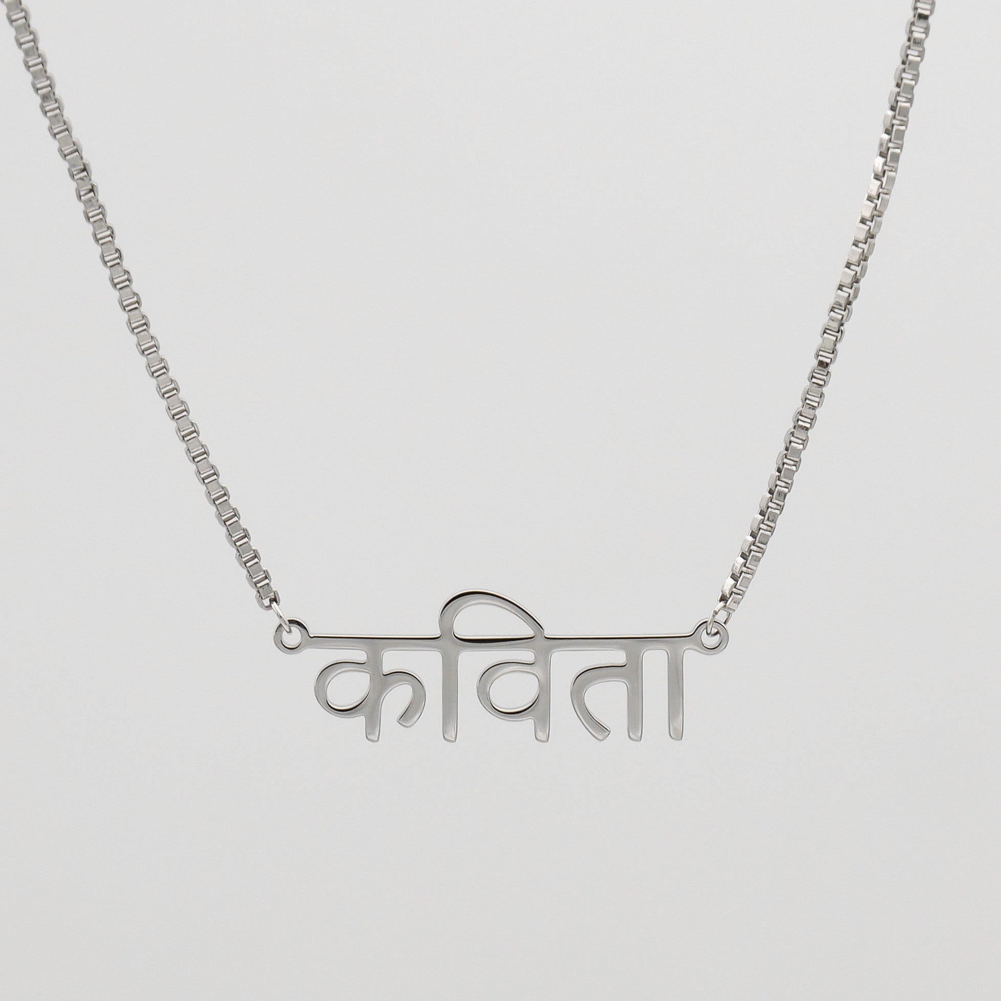 Silver Hindi name necklace suspended on a box chain
