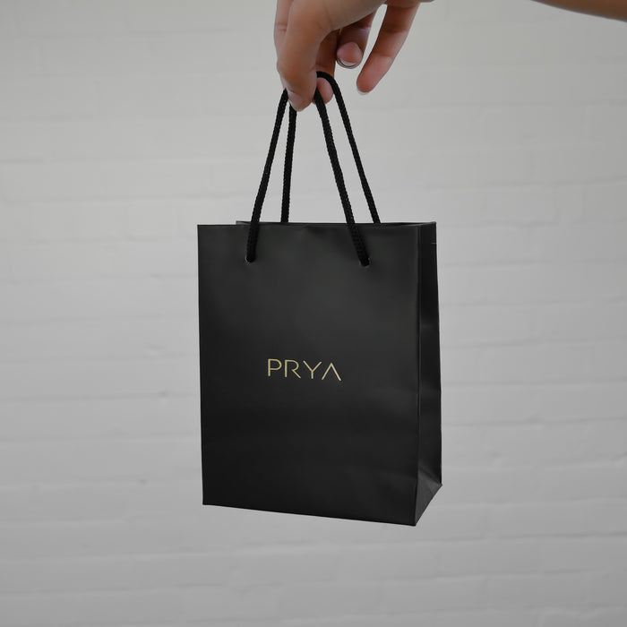 Hand holding a black PRYA gift bag.