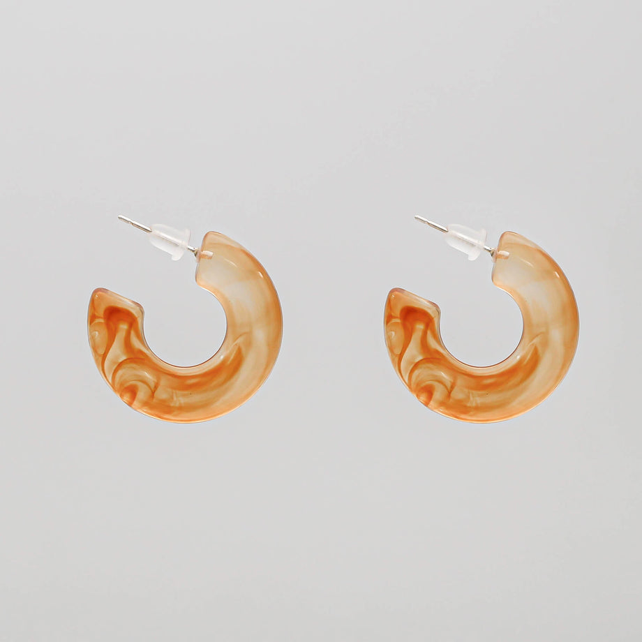 Orange marbled hoop earrings against white background.