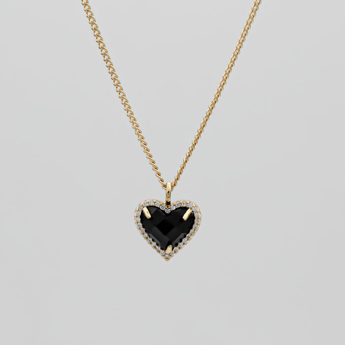 Gold necklace with black heart pendant.