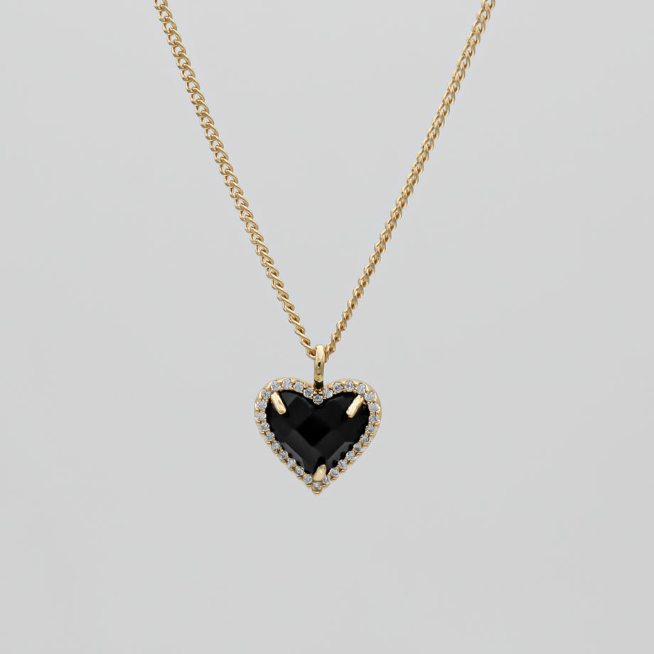 Gold necklace with black heart pendant.