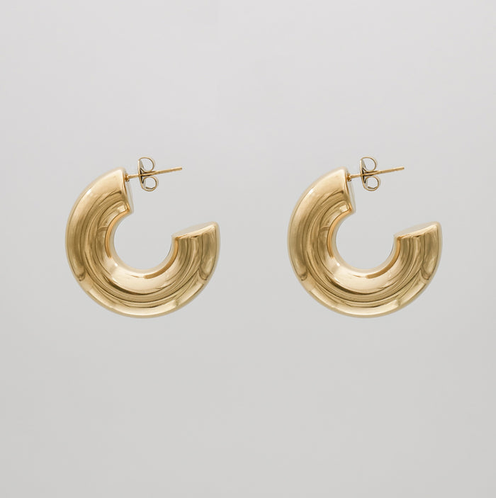 Gold hoop earrings against a grey background.