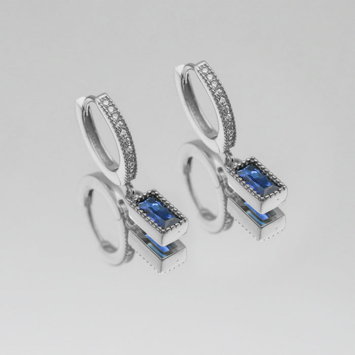 silver pave hoop earrings with blue gemstone pendants.