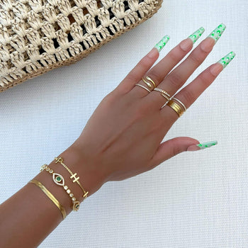 Model wearing Gold Evil Suspended bracelet paved with CZ diamonds and Emerald Green Gem