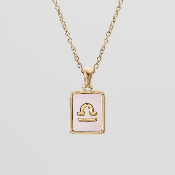 Gold Libra zodiac necklace with pink background.