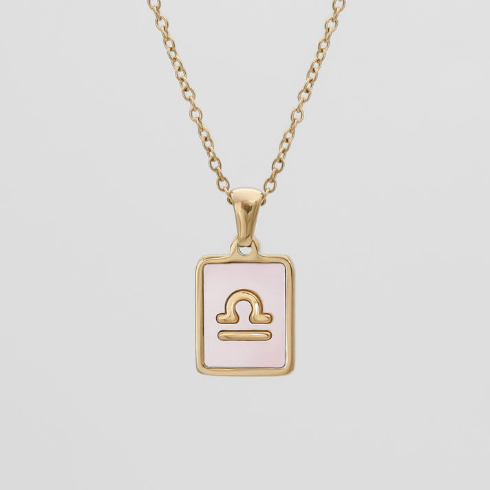 Gold Libra zodiac necklace with pink background.
