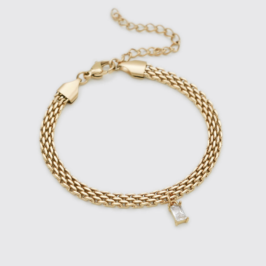 Gold bracelet with a clear gemstone charm.