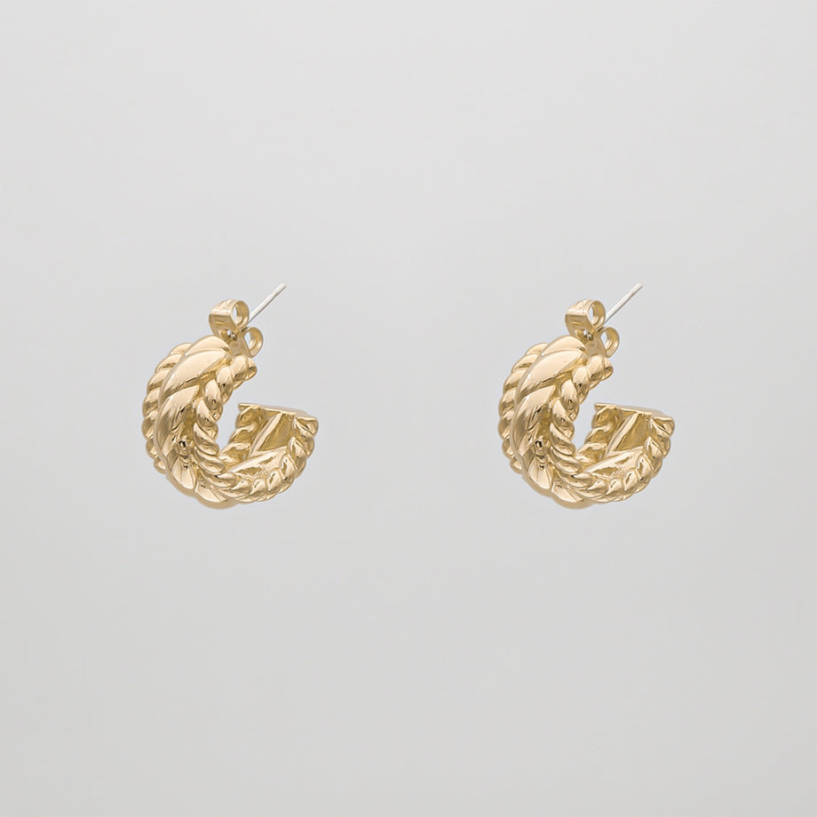 Gold twisted hoop earrings on white background.