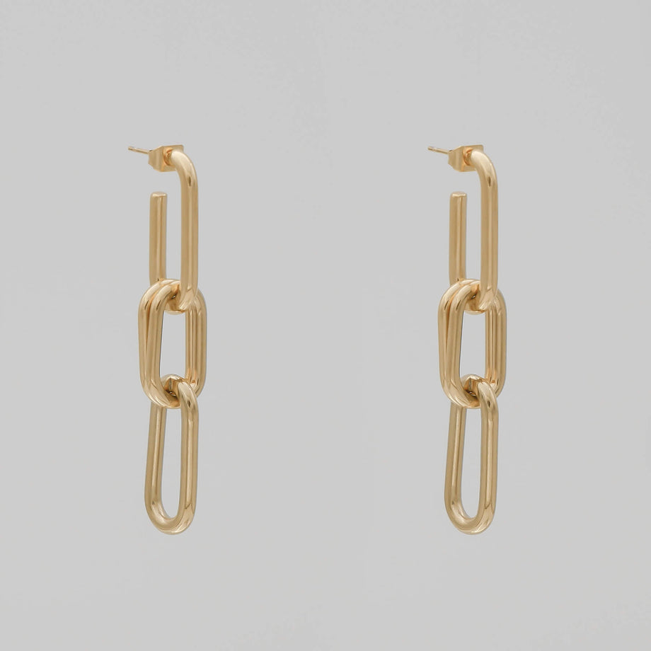 Gold chain link earrings on grey background.