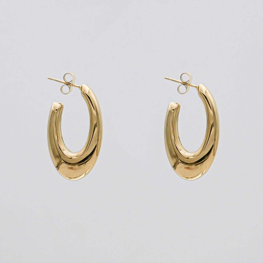 Gold oval hoop earrings on white background.