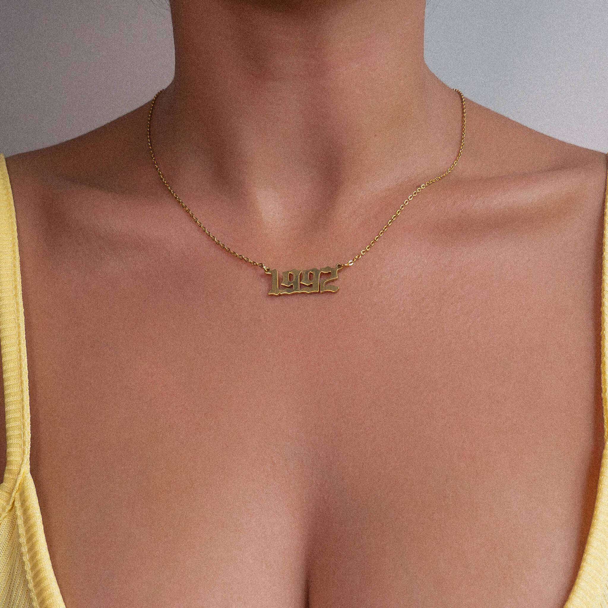 Woman wearing a yellow strappy top sporting a 1992 gold birth year chain necklace