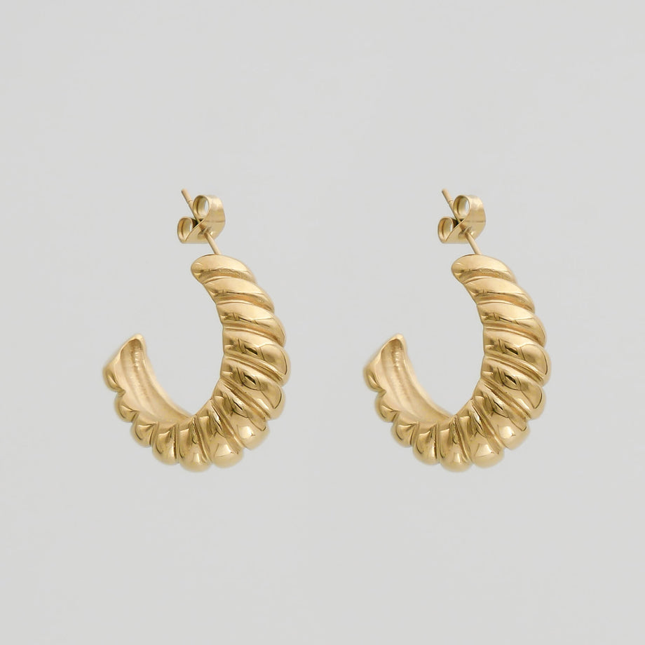 Gold textured hoop earrings on white background.