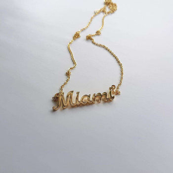 Gold custom name necklace laid on white surface